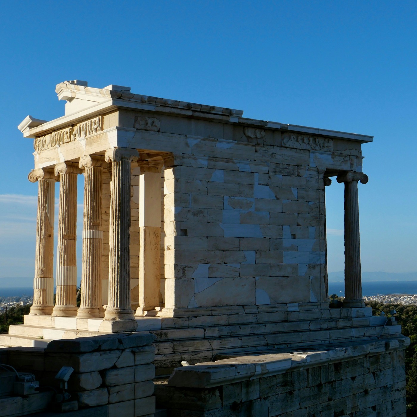 Ancient marble columns on the Acropolis above Athens, with the city and sea in the distance.